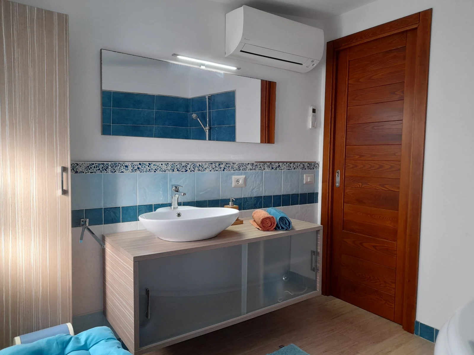 Il bagno con il lavabo d'appoggio e le piastrelle blu