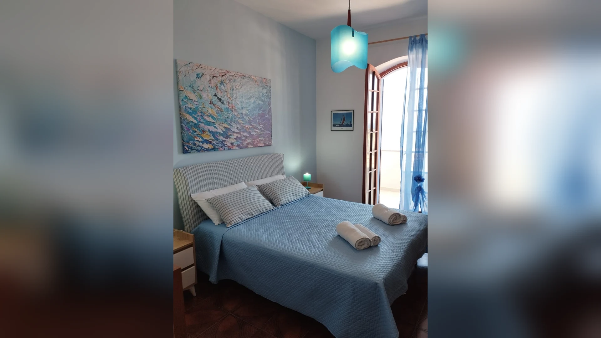 La camera matrimoniale con il copriletto blu e il quadro dei pesci