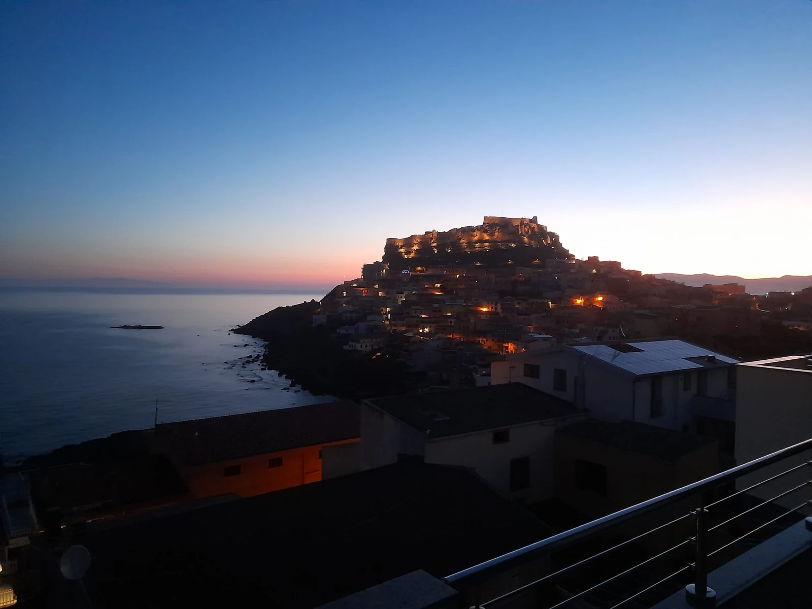 Il castello di Castelsardo illuminato all'imbrunire, visto dal terrazzo