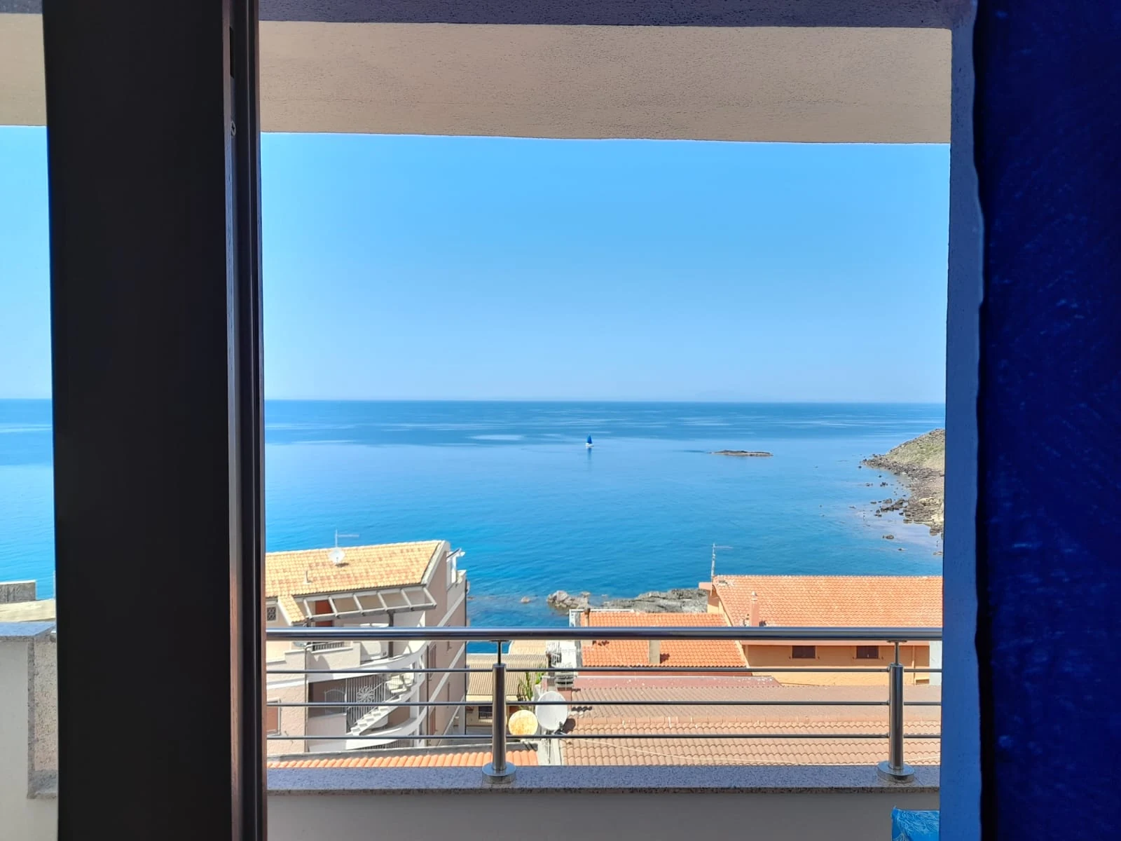 Il mare e i tetti del borgo visti attraverso la porta finestra