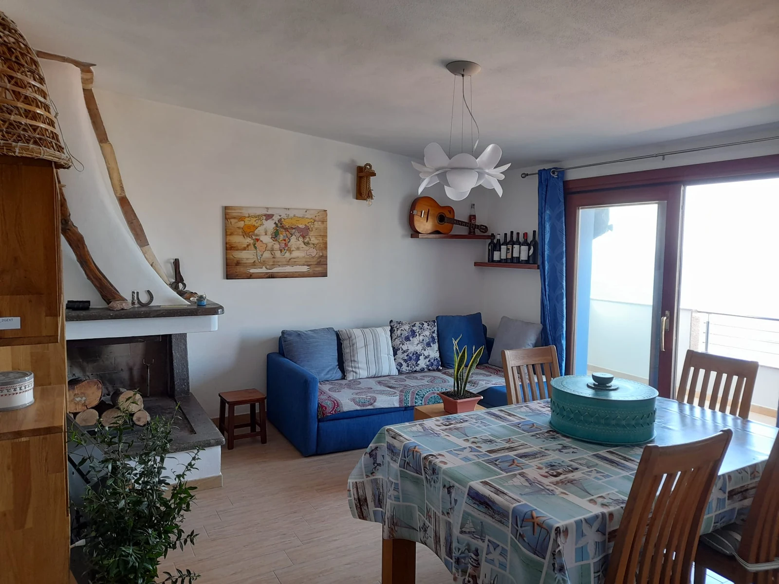 La zona giorno con il camino d'arredo, il divano blu e il tavolo da pranzo