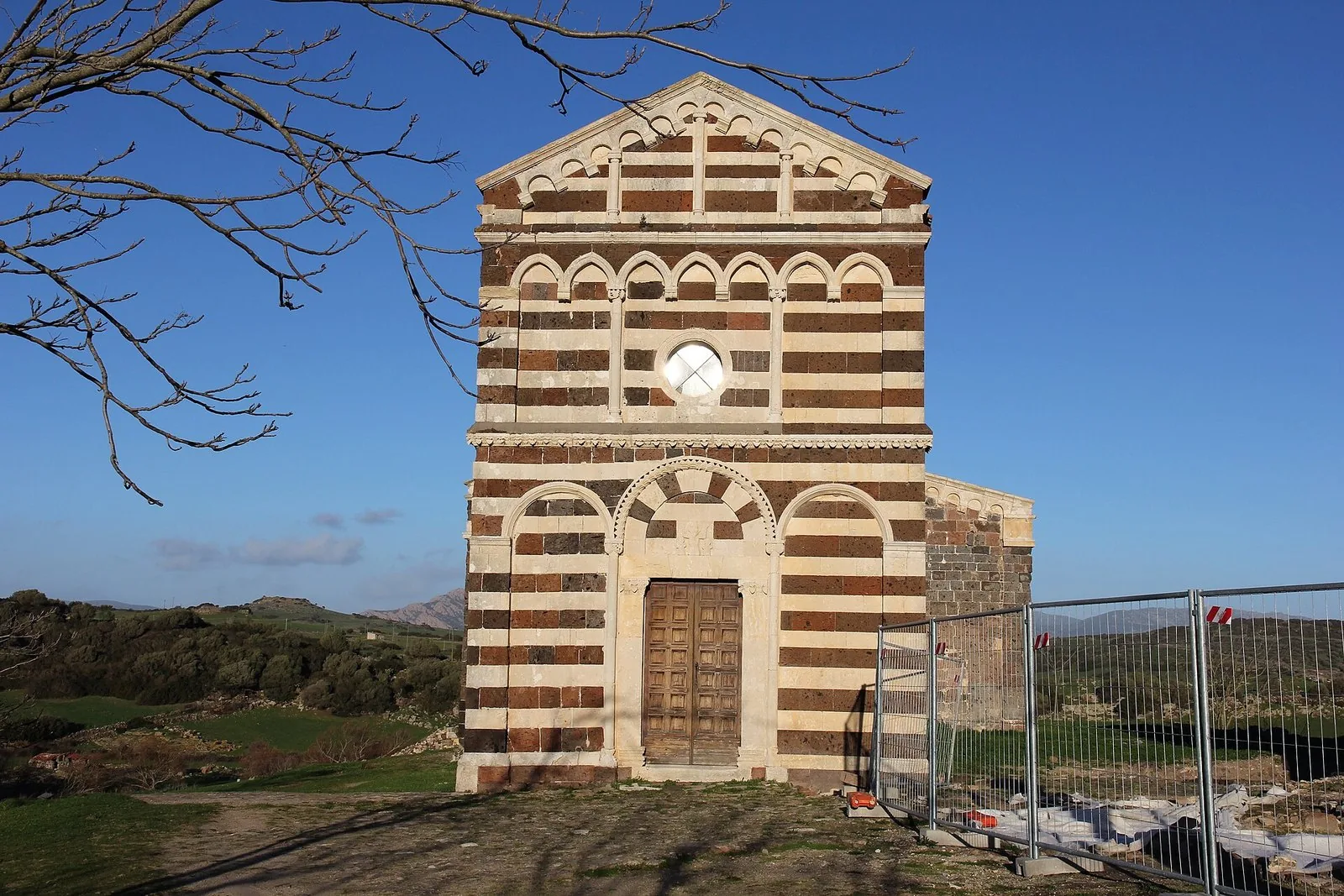 Facciata bicroma in trachite rosso-violacea e calcare bianco della chiesa romanica di Nostra Signora di Tergu