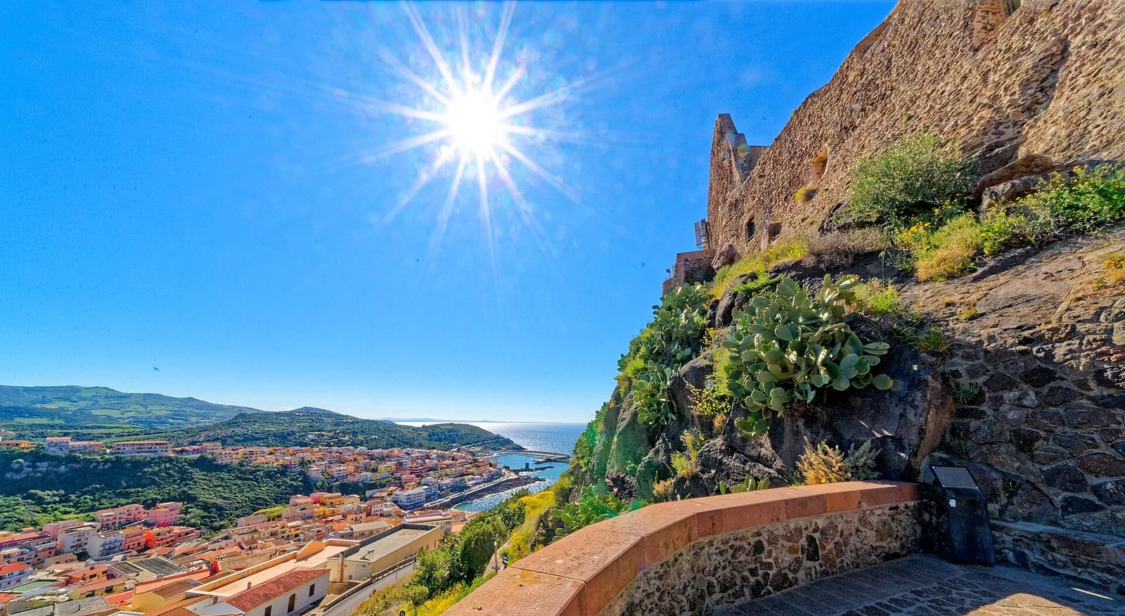 Il borgo di Castelsardo e il castello dei Doria illuminati al tramonto, visti dal mare